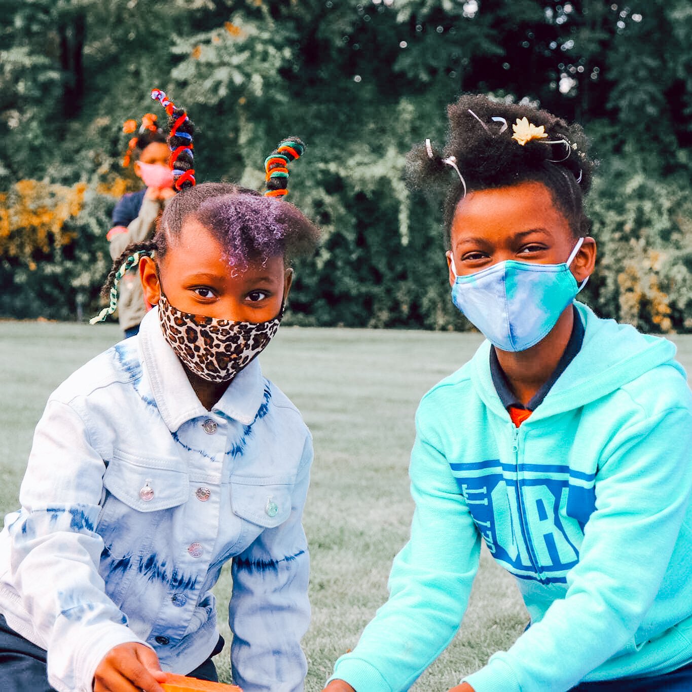 Two African American, female students smile under their masks. They are participating in crazy hair day. 