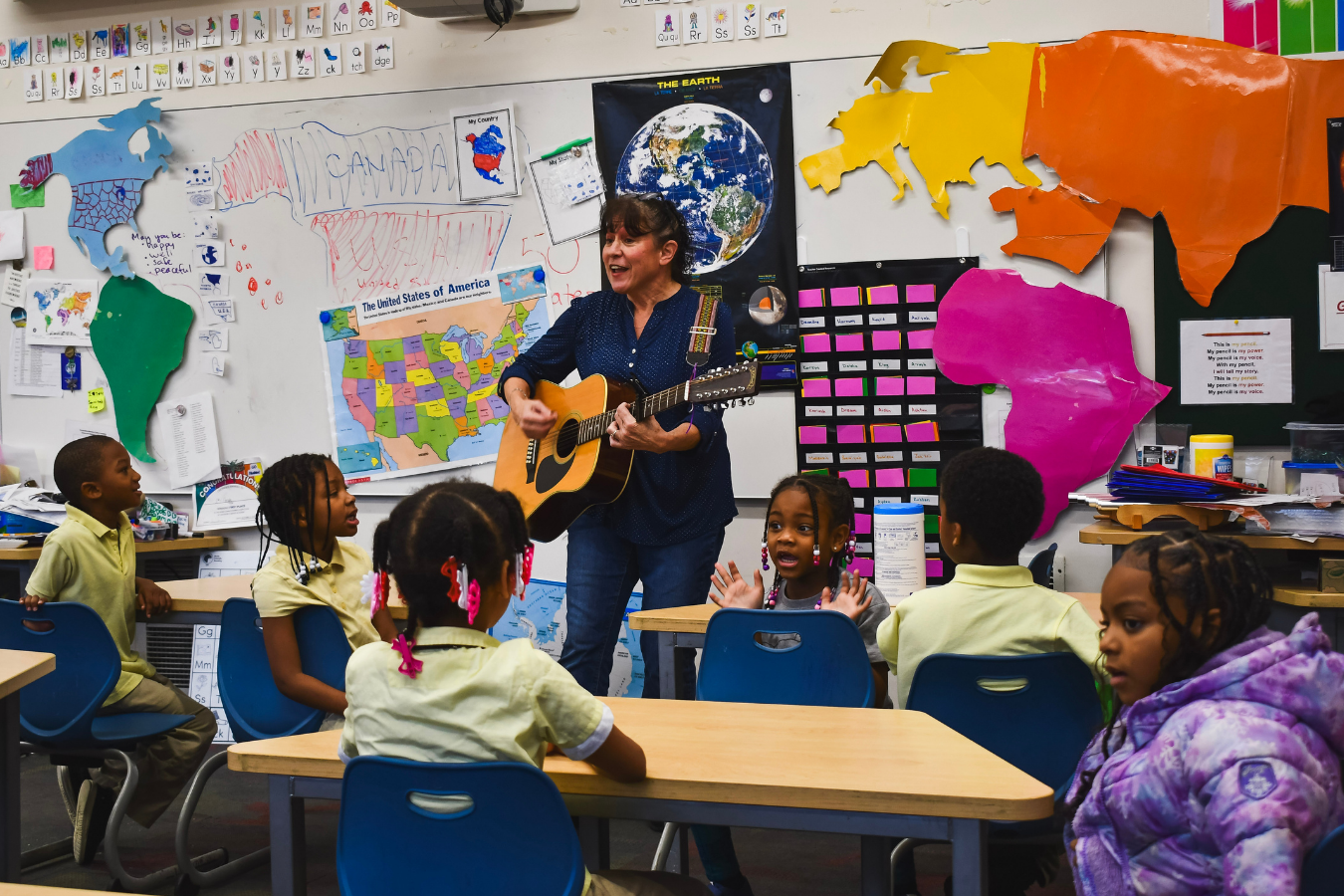 Teacher playing guitar in front of an elementary classroom