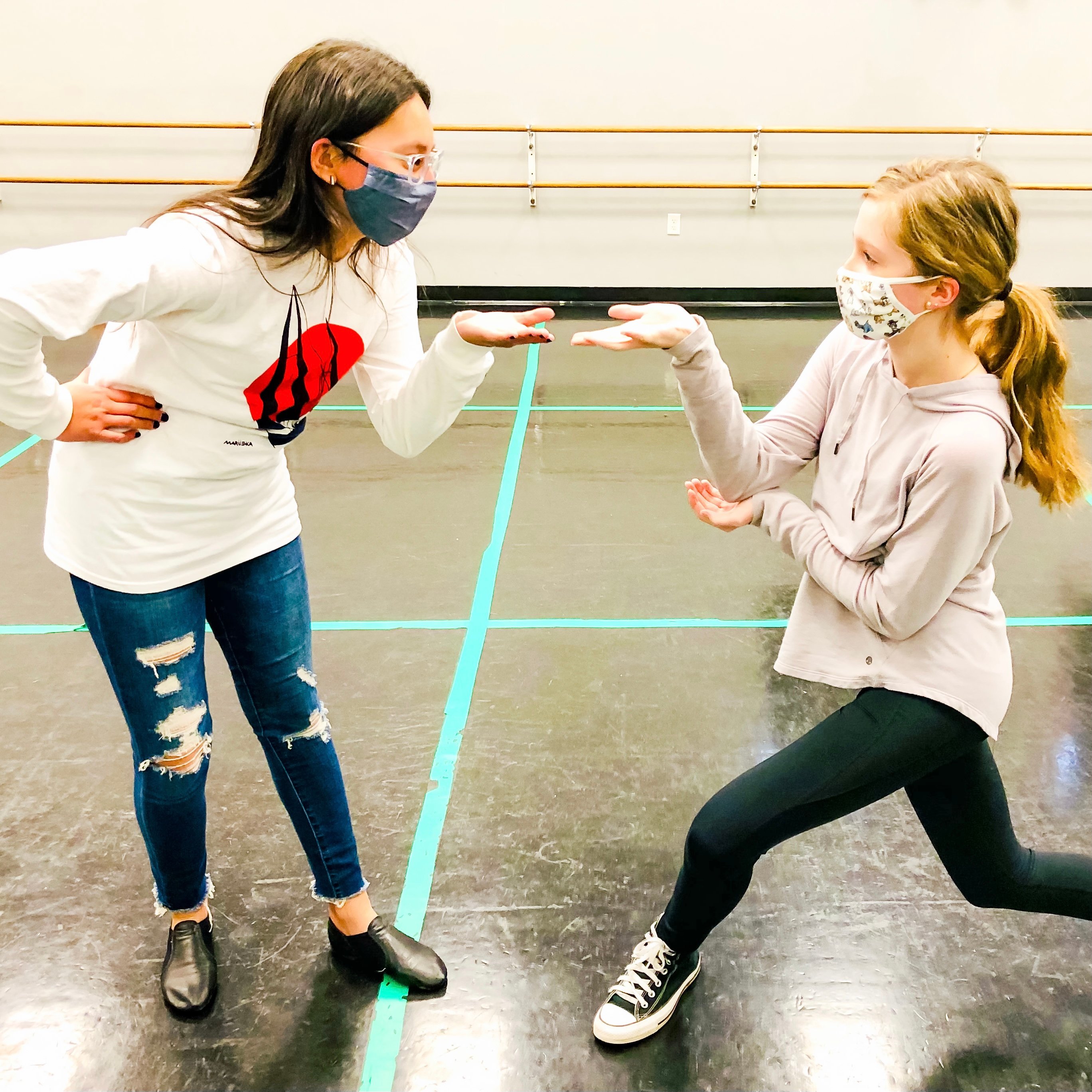 Two students stand facing each other in the middle of musical theatre practice