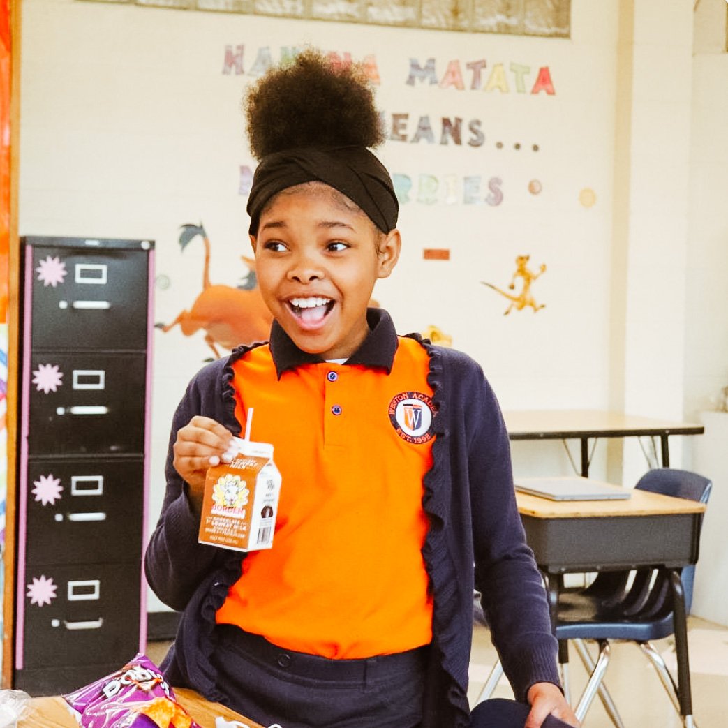 A photo of a female African American student stands with her mouth open with joy.