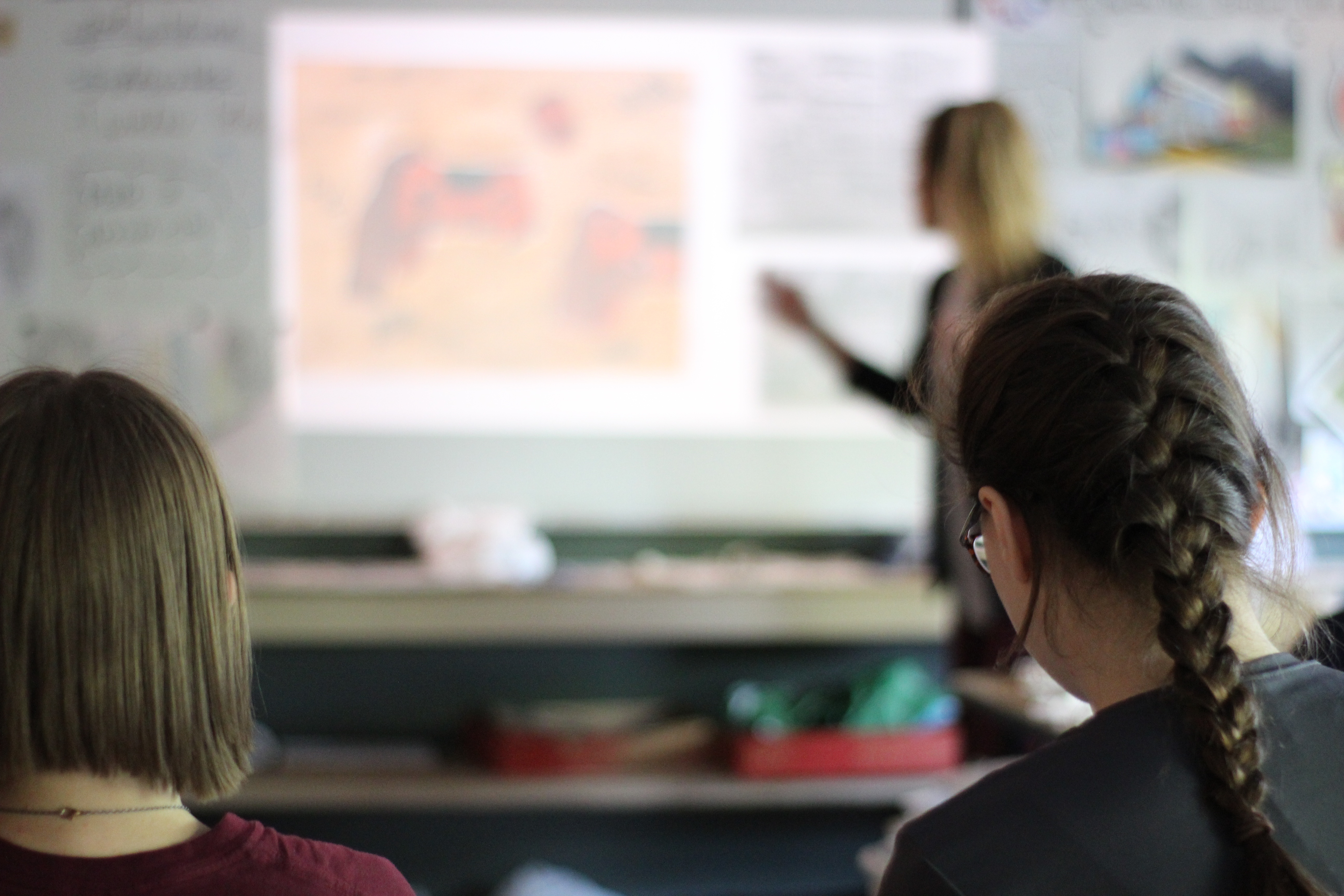 A photo of two female students taking notes on a presentation.