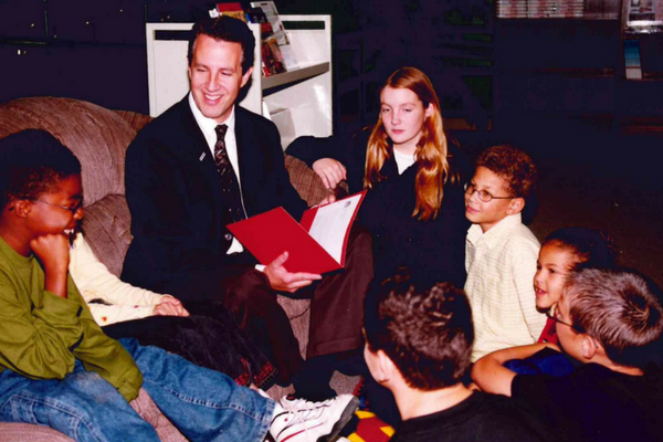 A historic photo of MAPSA President, Dan Quisenberry, reading to a group of students. 