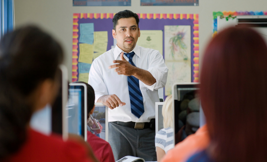 A photo of a man instructing students in a classroom. 