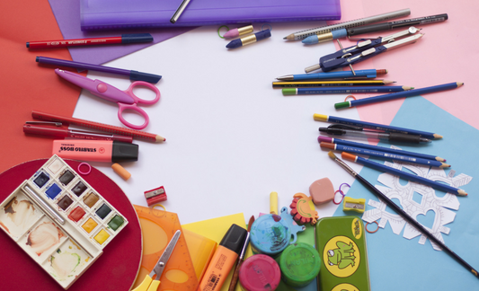 A colorful photo of school supplies and art supplies on a white table.