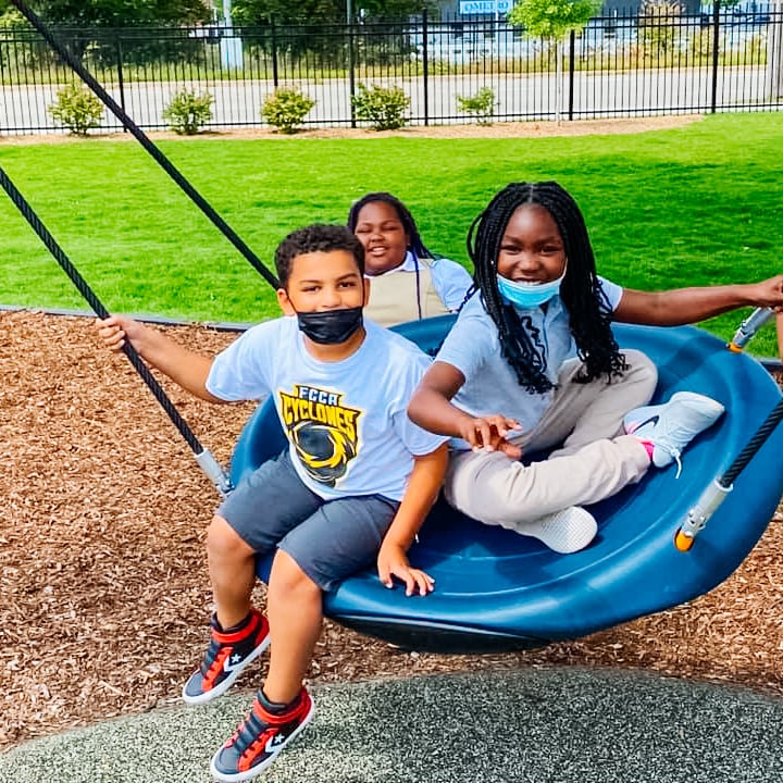Three students swing on a tire swing. 