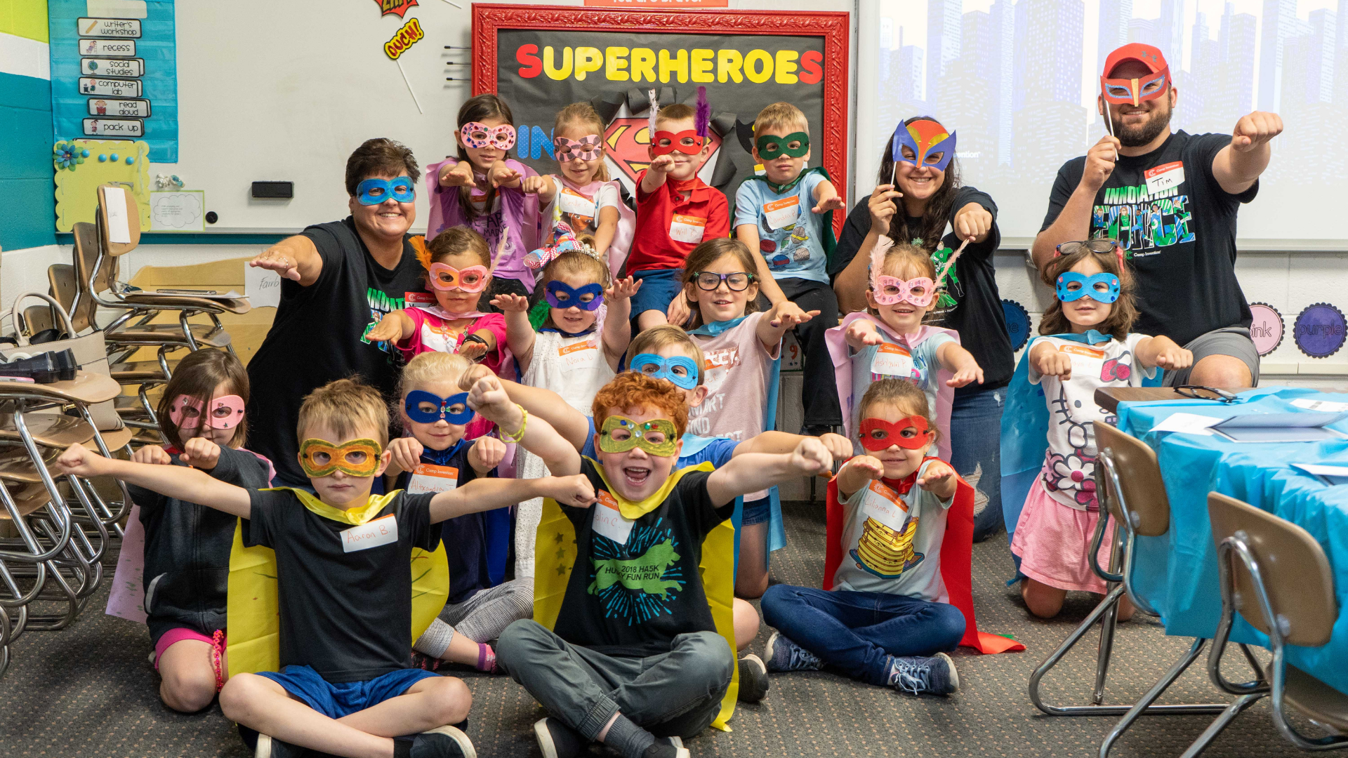 A group of students pose while dressed as superheroes in masks and capes. 
