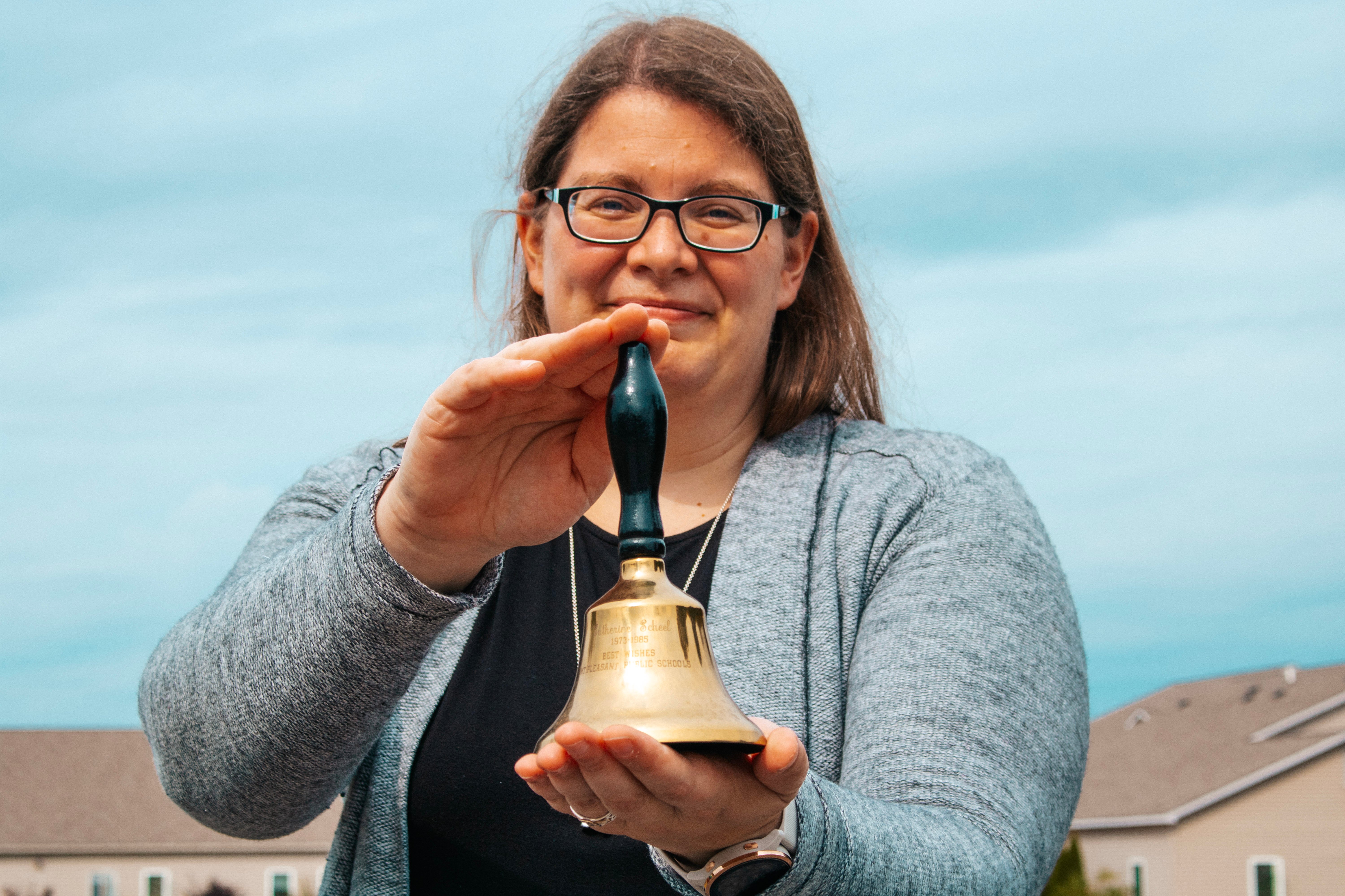 A photo of Concord Academy Boyne teacher, Caitlin Ritter, holding a bell that was given to her grandmother as a gift for her years of service as a teacher.