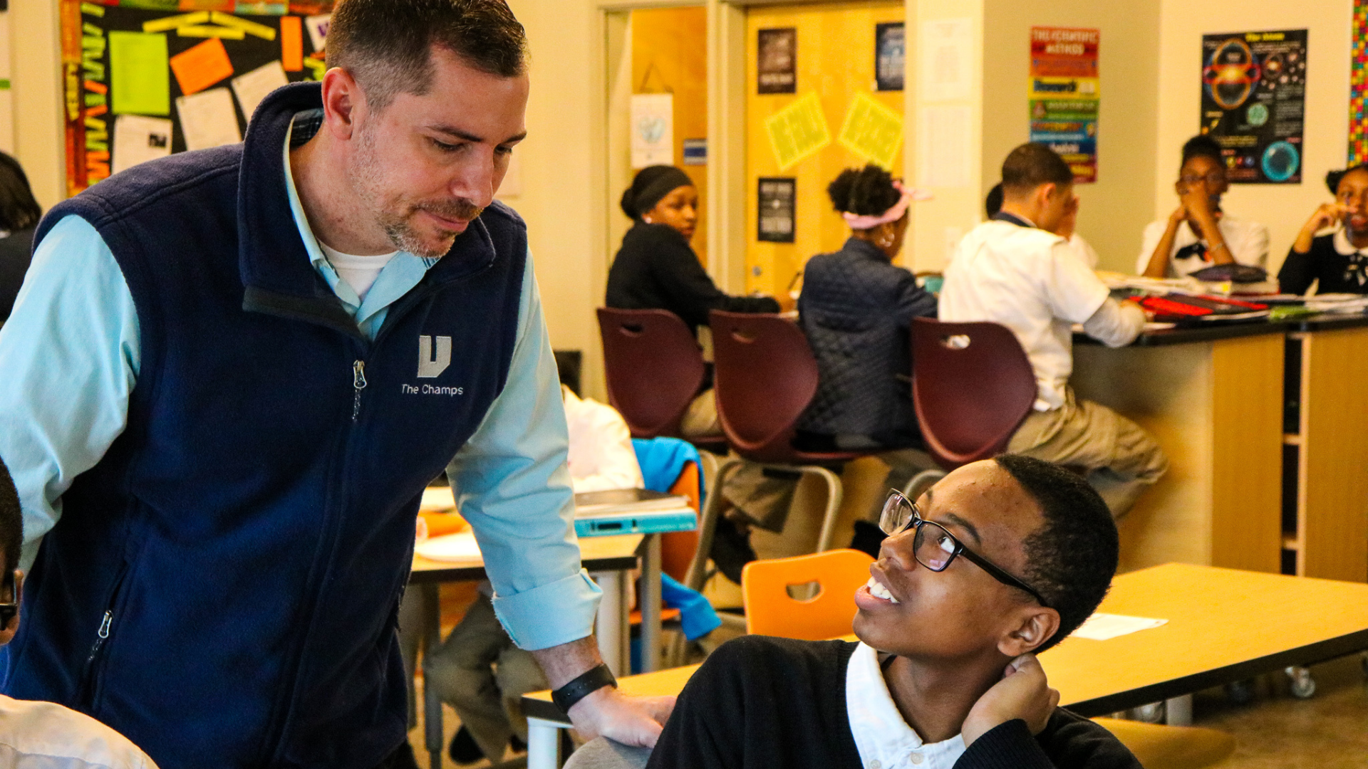 A photo of 2019 MI Charter Teacher of the Year, Joel Hockin in his UPrep Math & Science middle school classroom in Detroit, helping a student. 