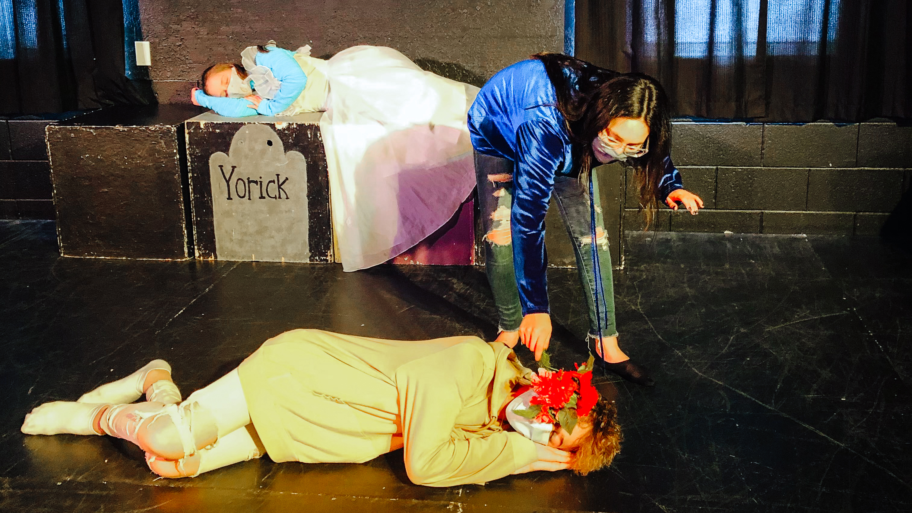 8th graders Lucy Herlein lays across a stage reaching down to another student during a production at West Michigan Academy of Arts and Academies