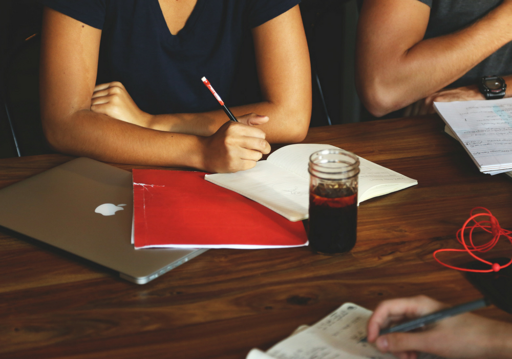 A photo of several people meeting at a large table.