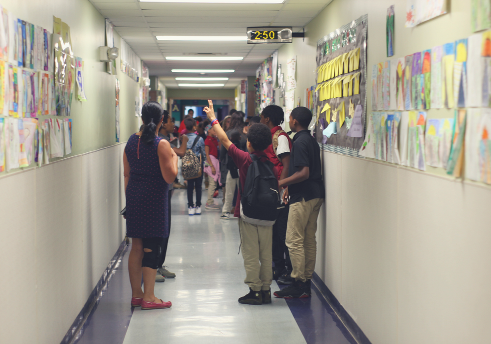 A photo of several students standing in a hallway and facing away from the camera.