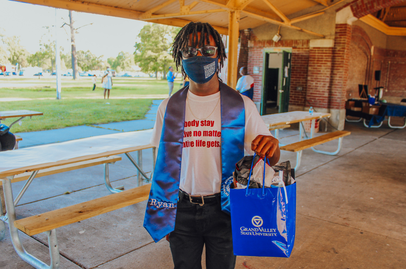 An African America student stands with a Grand Valley State University gift bag